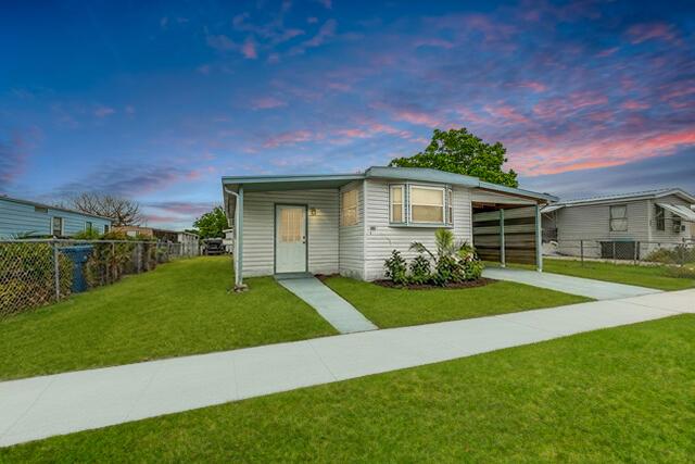 A single-story mobile home with light siding and a carport sits on a grassy lot — 2531 Chatham Way NE, Palm Bay FL 32905, PALM BAY, FL