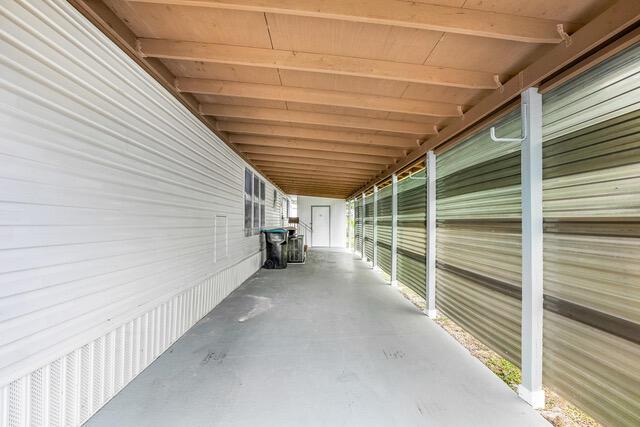 A long, covered carport with white siding, a concrete floor, and corrugated metal privacy walls — 2531 Chatham Way NE, Palm Bay FL 32905, PALM BAY, FL
