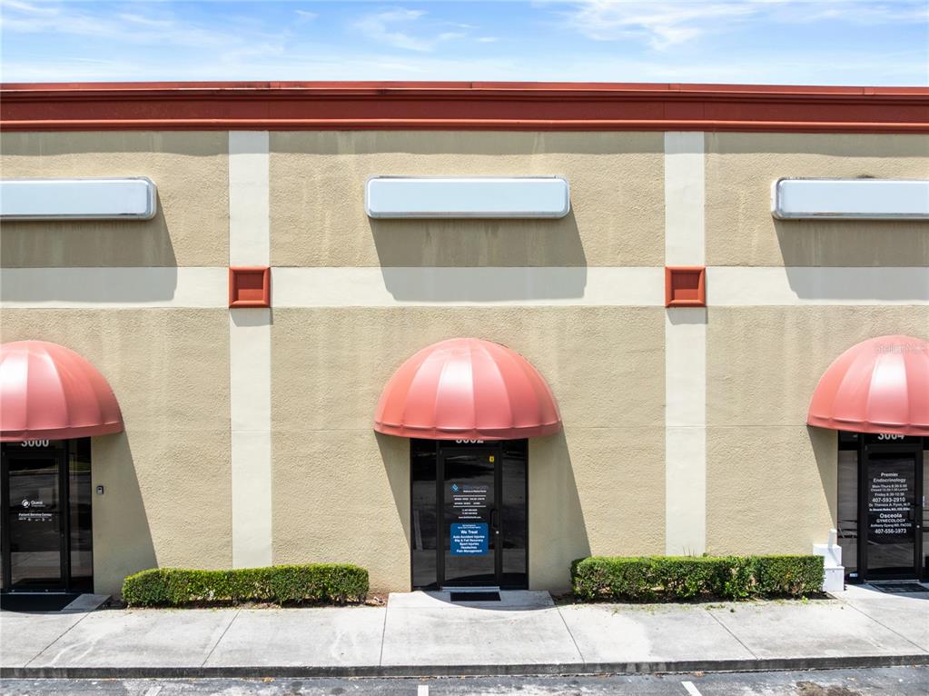 The exterior of a commercial building features three storefronts with red awnings and glass doors — 3002 17TH STREET, ST CLOUD, FL