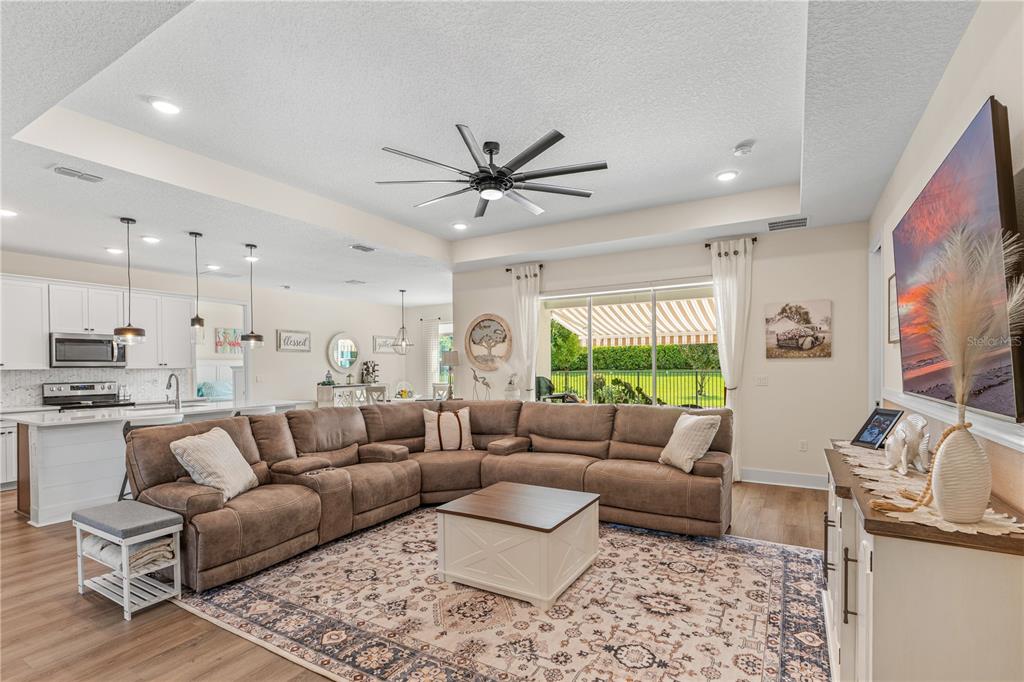 A spacious living room with a large sectional sofa, area rug, and open kitchen view — 3063 SILVERMINES AVENUE, ORMOND BEACH, FL