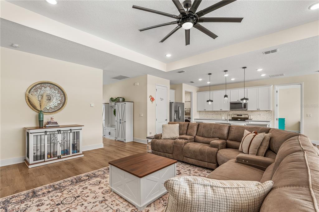 A living room with a brown sectional sofa, coffee table, and an open-concept kitchen — 3063 SILVERMINES AVENUE, ORMOND BEACH, FL