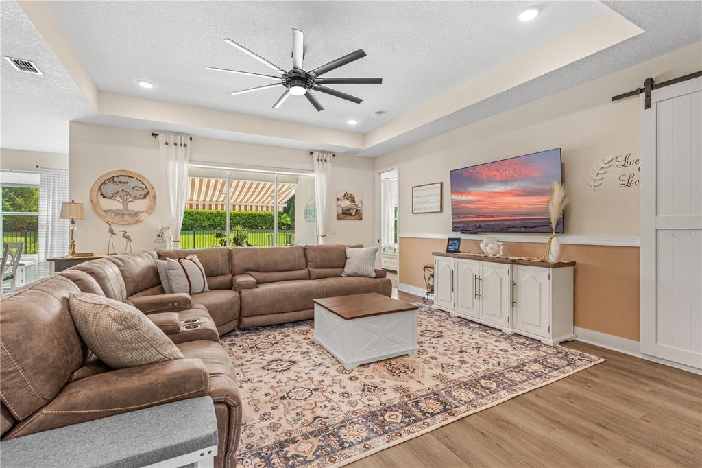 A living room features a large sectional sofa, a coffee table, and a wall-mounted television — 3063 SILVERMINES AVENUE, ORMOND BEACH, FL