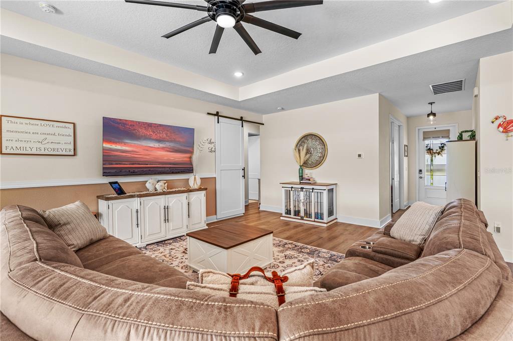 A living room features a large brown sectional sofa, a television, and a white barn door — 3063 SILVERMINES AVENUE, ORMOND BEACH, FL