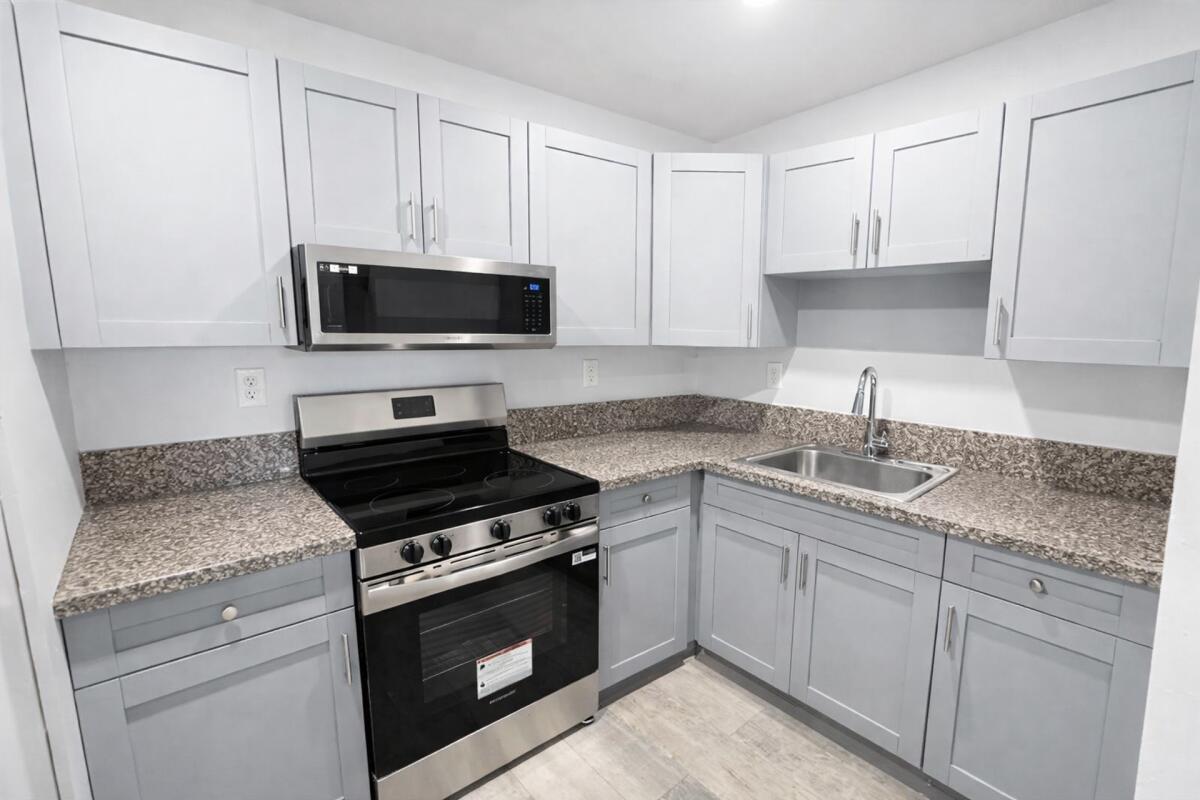 A kitchen with gray shaker cabinets, granite countertops, and stainless steel appliances — 3300 S Dixie Highway # 503, Miami FL 33133, MIAMI, FL