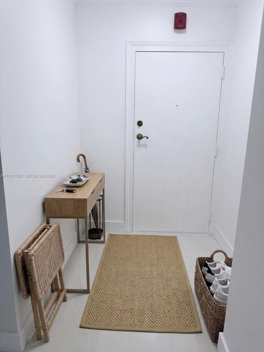 A minimalist entryway features a console table, a woven rug, and a basket of shoes — 160 SW 30th Ave # 104A, Miami FL 33135, MIAMI, FL