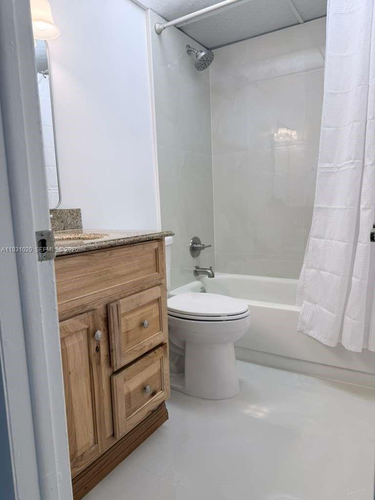 A bathroom features a wood vanity with a stone countertop, a toilet, and a tub-shower — 160 SW 30th Ave # 104A, Miami FL 33135, MIAMI, FL