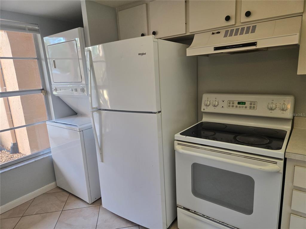 A kitchen featuring white appliances, including a stacked washer-dryer, refrigerator, and electric range — 6328 7TH AVENUE W UNIT 6328, BRADENTON, FL