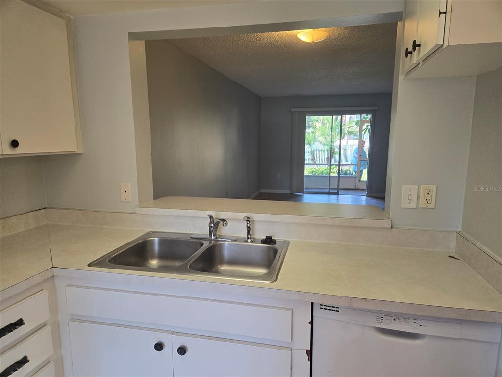 A kitchen sink and dishwasher are visible in front of a pass-through to a living area — 6328 7TH AVENUE W UNIT 6328, BRADENTON, FL