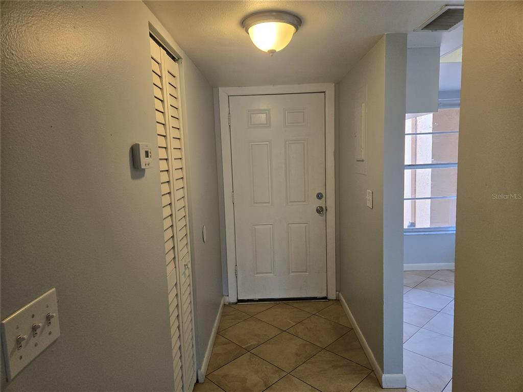 An entryway features a white door, tiled floor, a ceiling light, and a louvered closet door — 6328 7TH AVENUE W UNIT 6328, BRADENTON, FL