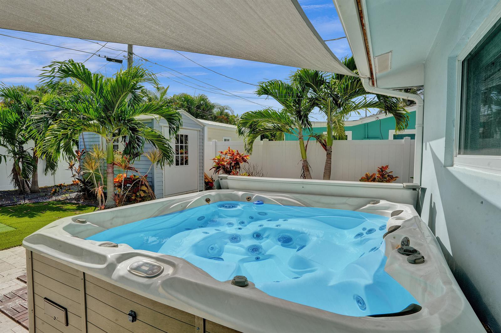 A hot tub sits on a patio under a shade sail near a small shed — 604 NE 25th Avenue, Pompano Beach FL 33062, POMPANO BEACH, FL