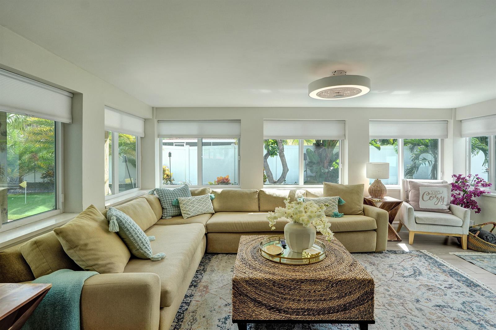 A bright living room features a large beige sectional sofa, a woven coffee table, and windows — 604 NE 25th Avenue, Pompano Beach FL 33062, POMPANO BEACH, FL