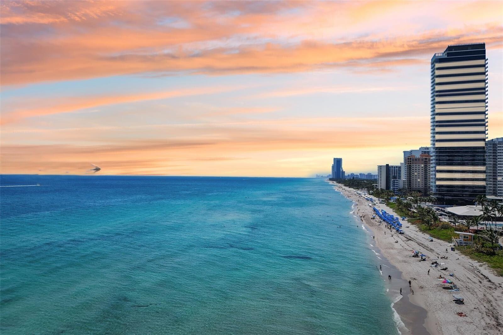 An aerial view of a sandy beach coastline with high-rise buildings under a sunset sky — 2000 S Ocean Drive SE # 5a, Hallandale Beach FL 33009, HALLANDALE BEACH, FL