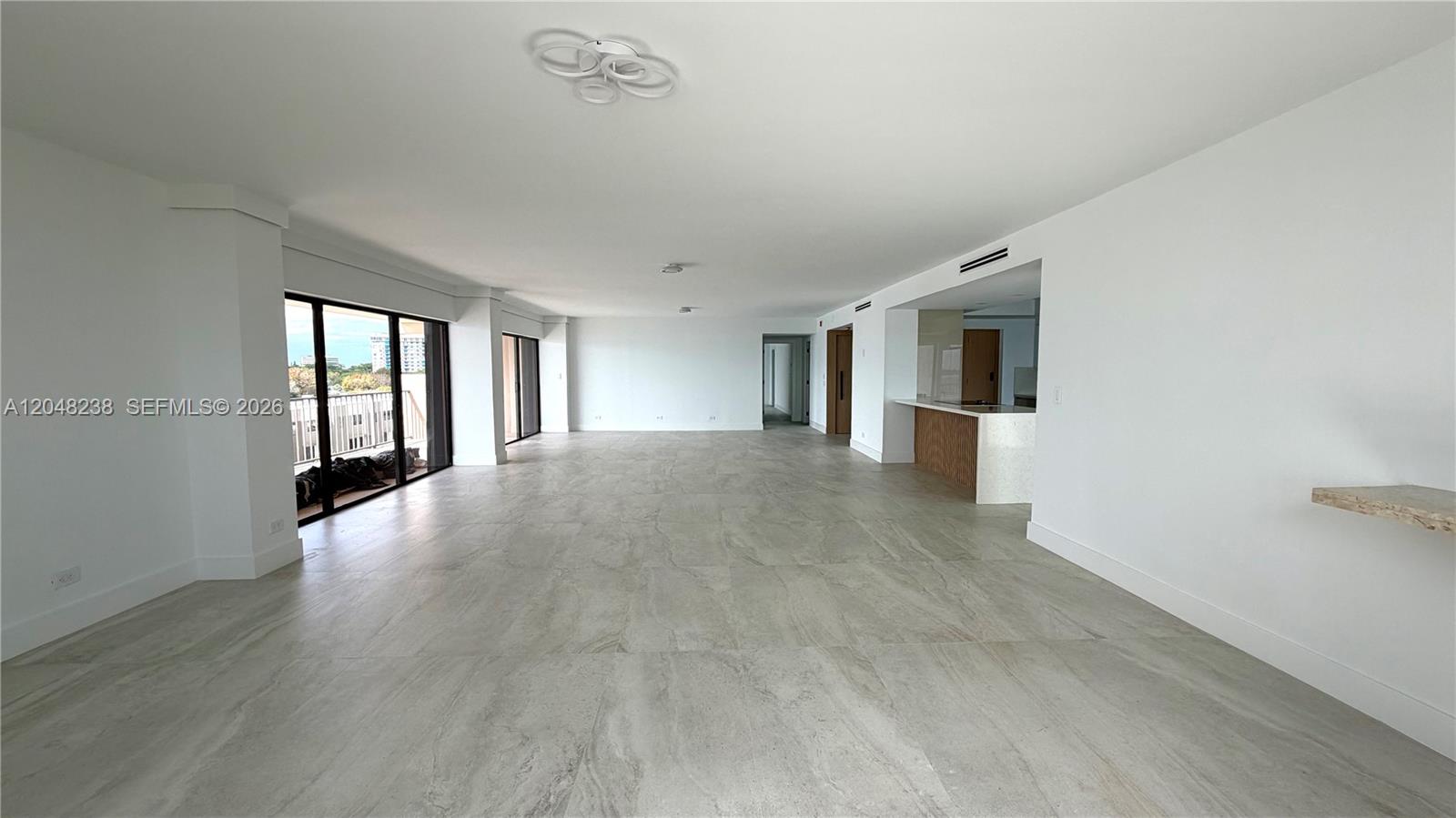 An open-concept living area features light-colored tile flooring, white walls, and a kitchen island — 1800 NE 114th # 604, North Miami FL 33181, NORTH MIAMI, FL