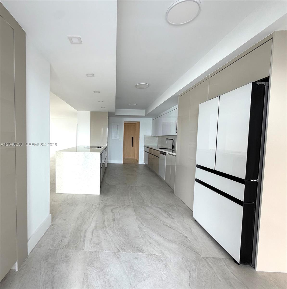 A modern kitchen features light-toned cabinetry, a white island, and large-format gray floor tiles — 1800 NE 114th # 604, North Miami FL 33181, NORTH MIAMI, FL