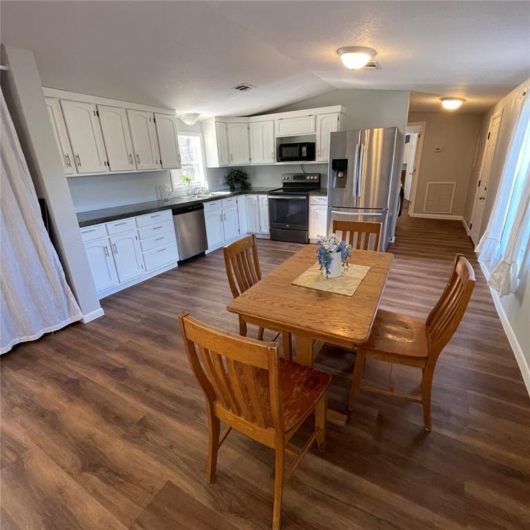 A kitchen with white cabinets, stainless steel appliances, and a wooden dining table — 8771 NE 107TH COURT, BRONSON, FL