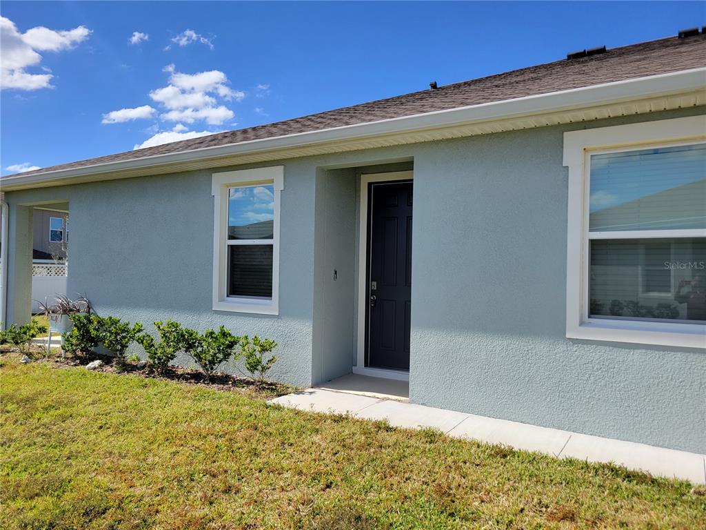 The exterior of a light blue house features a dark front door and white trim — 7788 STONEBROOK CIRCLE, WESLEY CHAPEL, FL