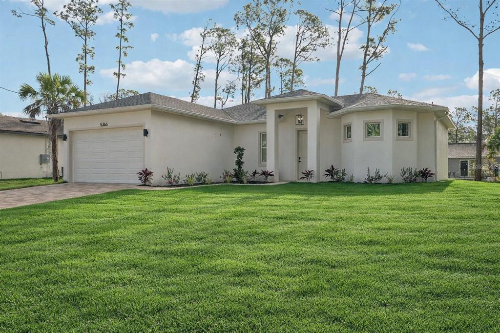 A single-story house with a white stucco exterior, a two-car garage, and a green lawn — 4338 JODY AVENUE, NORTH PORT, FL
