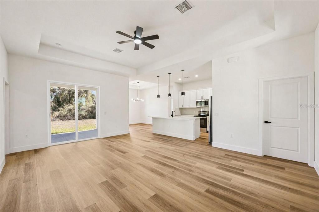 An open-concept living area features light wood flooring, a tray ceiling, and a modern kitchen — 4338 JODY AVENUE, NORTH PORT, FL