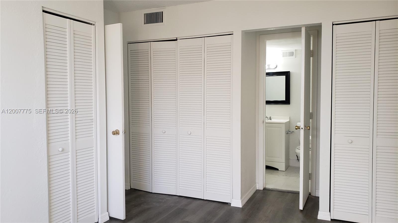 A room with white louvered closet doors and an open doorway leading to a bathroom — 1251 NE 108th St # 215, Miami FL 33161, MIAMI, FL