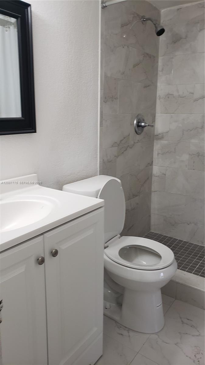 A bathroom features a white vanity, a toilet, and a tiled walk-in shower — 1251 NE 108th St # 215, Miami FL 33161, MIAMI, FL