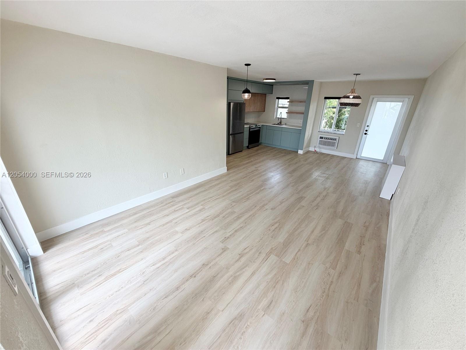 An open-concept living area features light wood-look flooring, neutral walls, and a modern kitchen — 641 Espanola Way # 17, Miami Beach FL 33139, MIAMI BEACH, FL