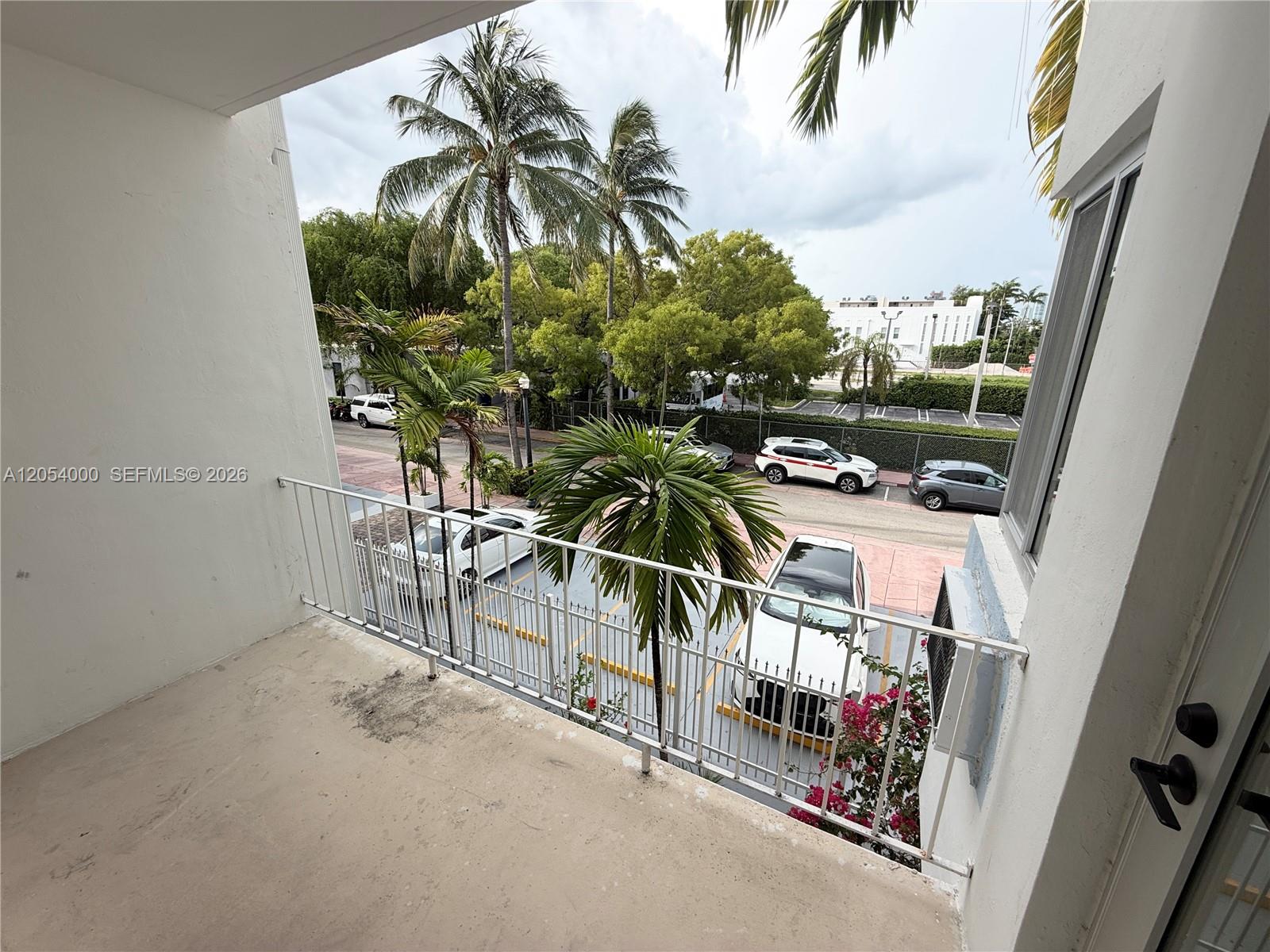 A balcony overlooks a parking lot with several cars and palm trees — 641 Espanola Way # 17, Miami Beach FL 33139, MIAMI BEACH, FL