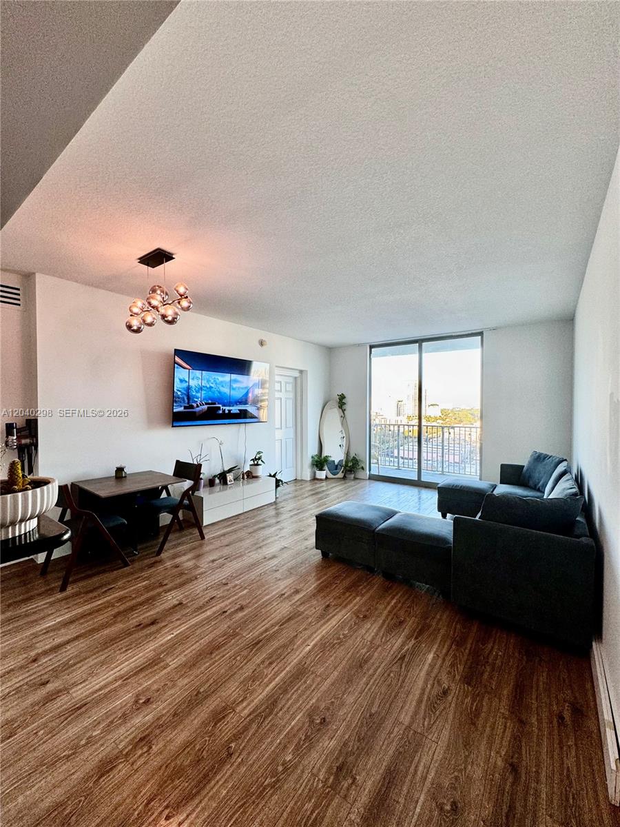 A living and dining area features wood-look flooring, a dark sectional sofa, and a balcony — 140 S Dixie Hwy # 921, Hollywood FL 33020, HOLLYWOOD, FL