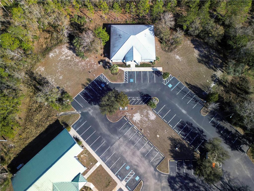 An aerial view shows a building with a metal roof and an adjacent parking lot — 8427 S SUNCOAST BOULEVARD, HOMOSASSA, FL