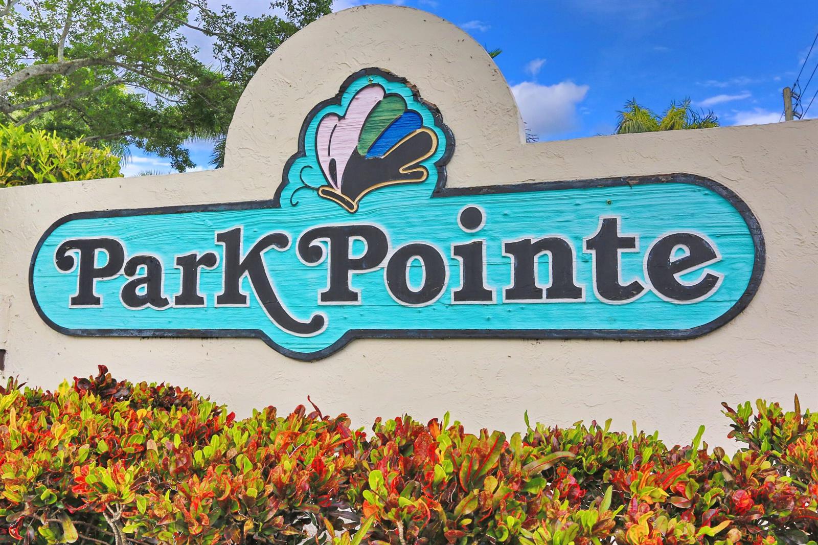 A teal sign reading Park Pointe sits on a beige wall behind colorful garden shrubs — 3277 Jog Park Drive, FL 33467, FL
