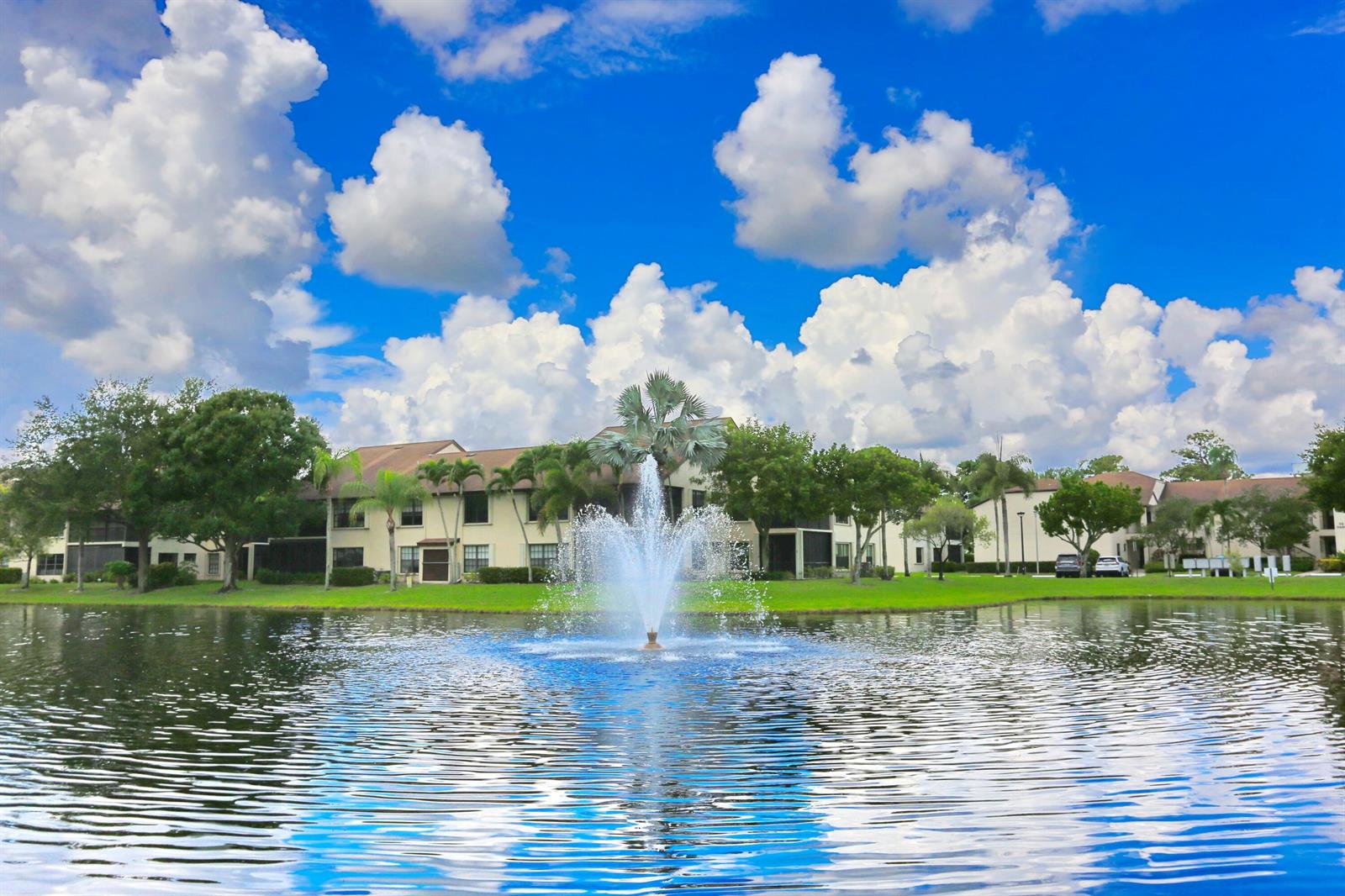A fountain sprays water in a pond in front of apartment buildings under a cloudy sky — 3277 Jog Park Drive, FL 33467, FL