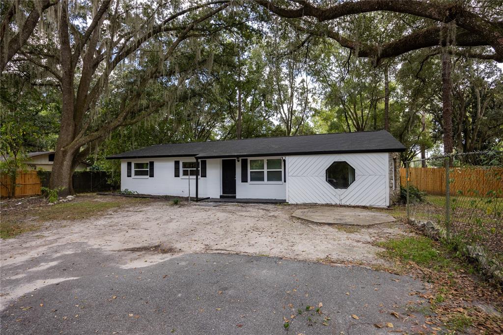 A single-story white house with a black roof, diagonal siding, and a sandy front yard — 14637 NE 145TH AVENUE, WALDO, FL
