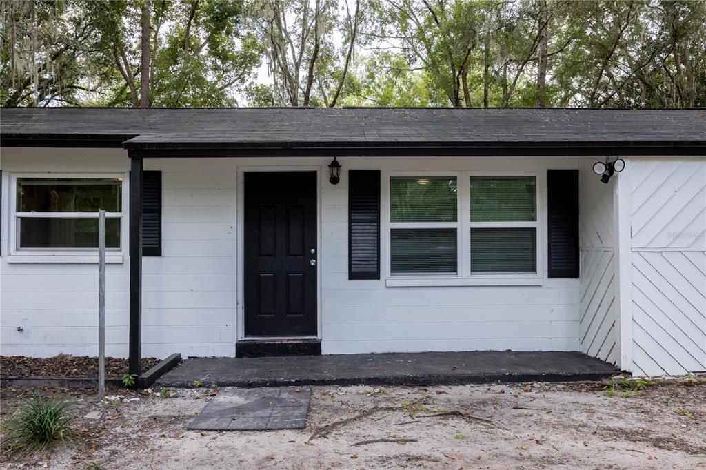 The exterior of a white, single-story house features a black front door and black shutters — 14637 NE 145TH AVENUE, WALDO, FL