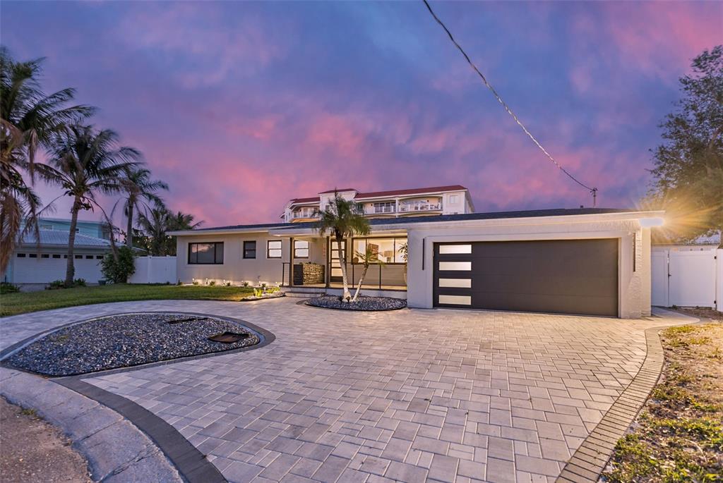 A single-story house with a paved driveway, a modern garage door, and a palm tree — 1866 VENETIAN POINT DRIVE, CLEARWATER, FL