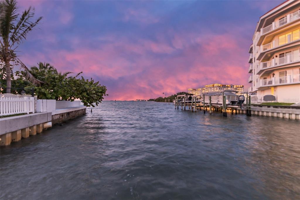 A view of a canal at sunset with a multi-story building and boat docks — 1866 VENETIAN POINT DRIVE, CLEARWATER, FL