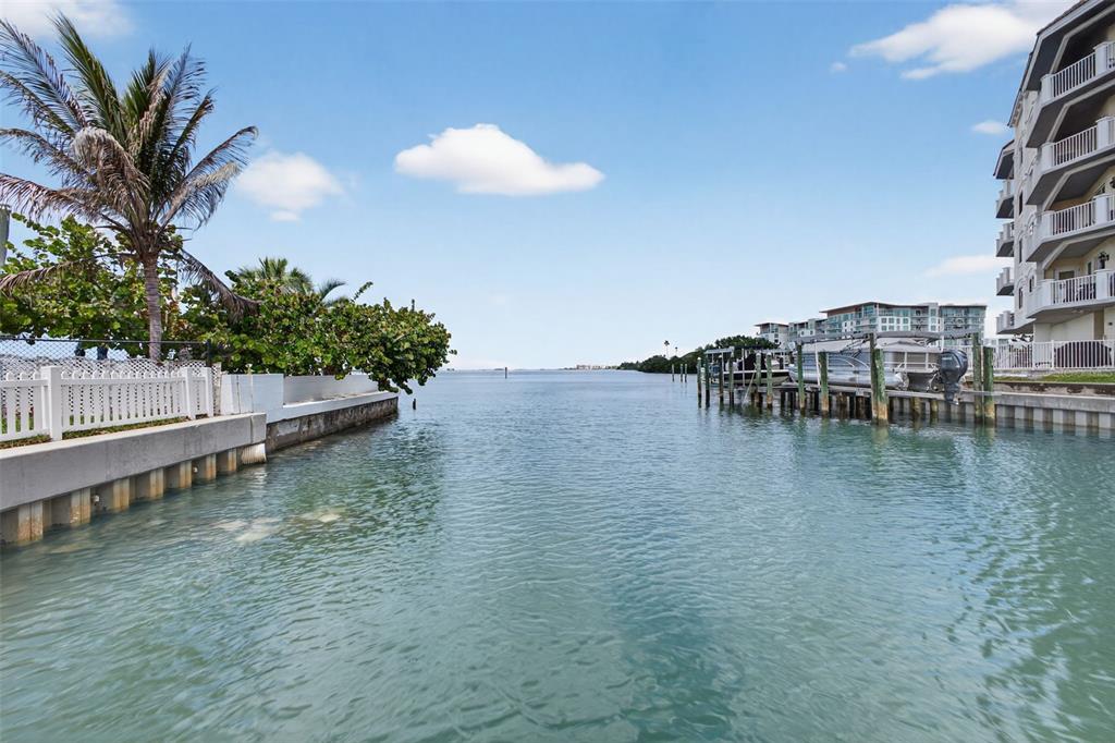 A view of a canal leading to open water, flanked by a palm tree and buildings — 1866 VENETIAN POINT DRIVE, CLEARWATER, FL