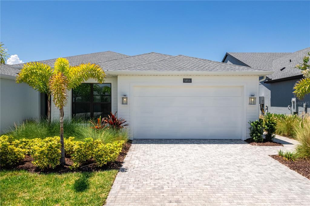 A white single-story house features a two-car garage, a paved driveway, and palm tree landscaping — 5854 WINDBREAK COURT, APOLLO BEACH, FL