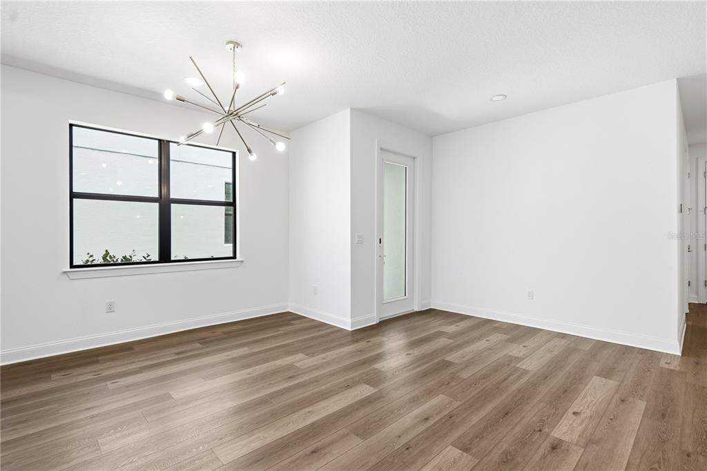 A dining room with white walls, wood-look flooring, a modern chandelier, and a glass-paneled door — 5854 WINDBREAK COURT, APOLLO BEACH, FL