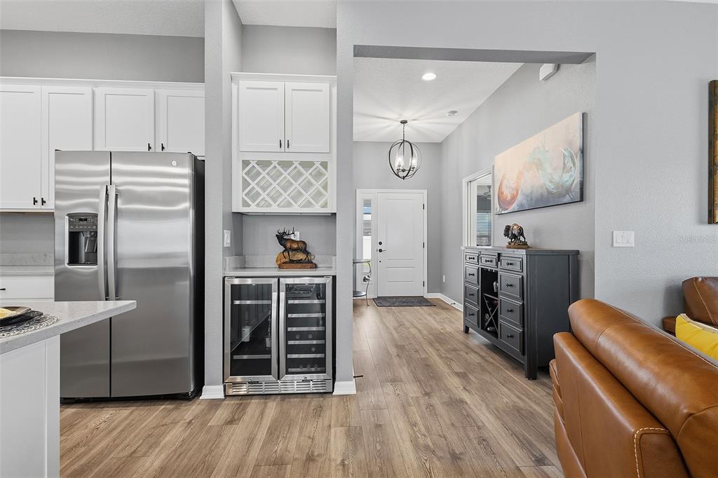 A kitchen features a stainless steel refrigerator, a wine cooler, and a white cabinet hutch — 6716 BUDDY LANE, THE VILLAGES, FL