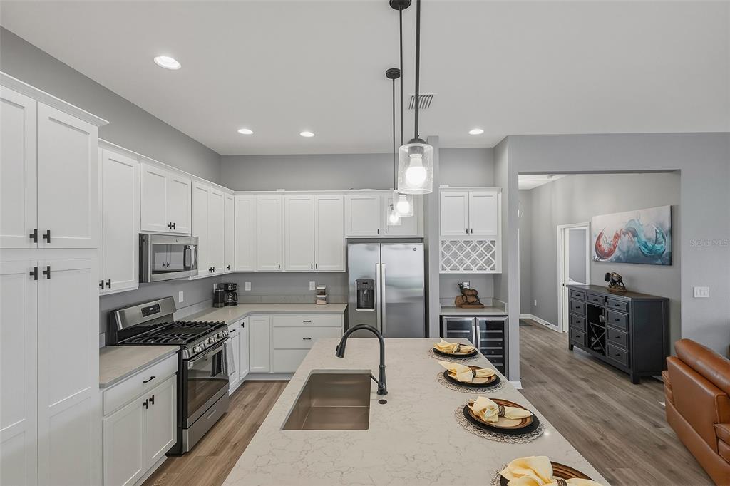 A modern kitchen features white cabinets, stainless steel appliances, and a large central island — 6716 BUDDY LANE, THE VILLAGES, FL