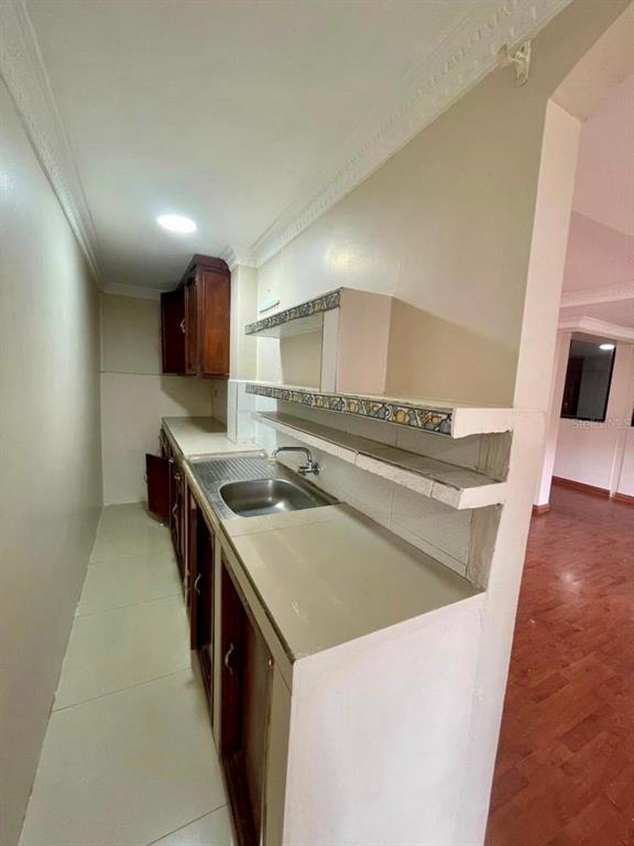 A narrow kitchen features wooden cabinets, a stainless steel sink, and decorative tiled shelving — 77 FRANCISCO LECARO, LOJA/ECUADOR, OC