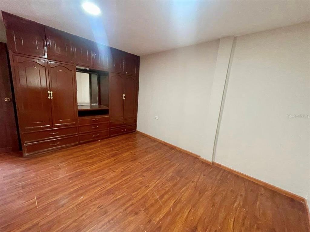 A bedroom features wood-look flooring, light-colored walls, and a large built-in wooden wardrobe — 77 FRANCISCO LECARO, LOJA/ECUADOR, OC