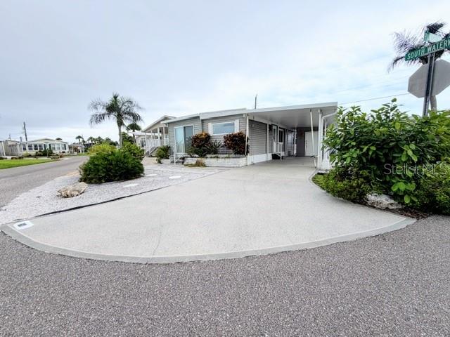 A single-story manufactured home features a concrete driveway, a carport, and surrounding landscaping — 801 S WATERWAY, VENICE, FL