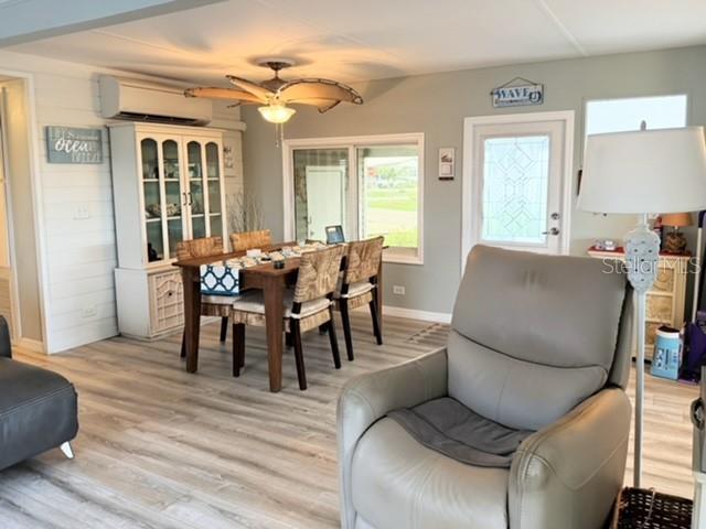 A dining area and living space feature light wood flooring, a ceiling fan, and furniture — 801 S WATERWAY, VENICE, FL