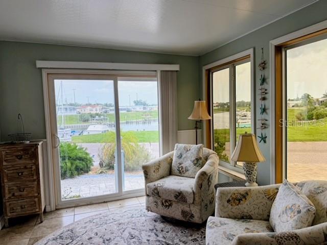 A sunroom features tile floors, patterned armchairs, and sliding glass doors overlooking a canal — 801 S WATERWAY, VENICE, FL