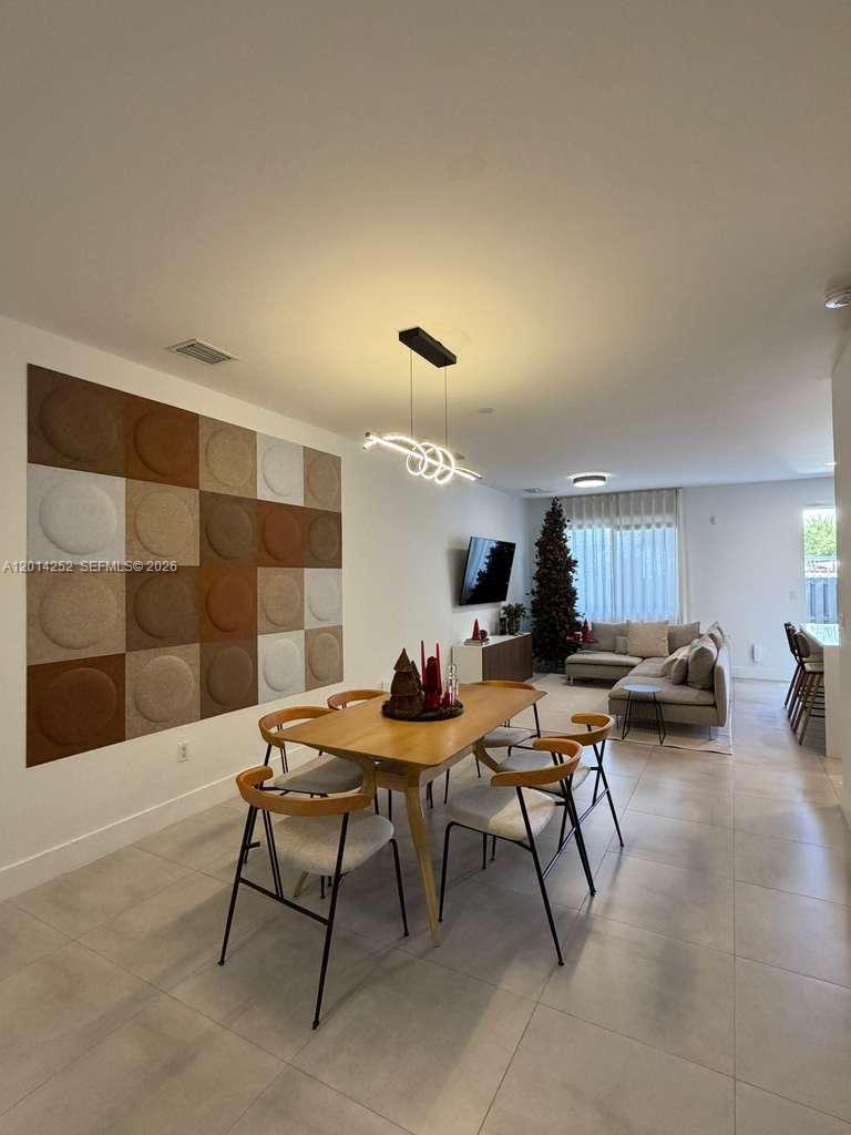 An open-concept living and dining area features a textured wall panel and modern lighting — 7187 NW 103 PATH # 7187, Miami FL 33178, MIAMI, FL