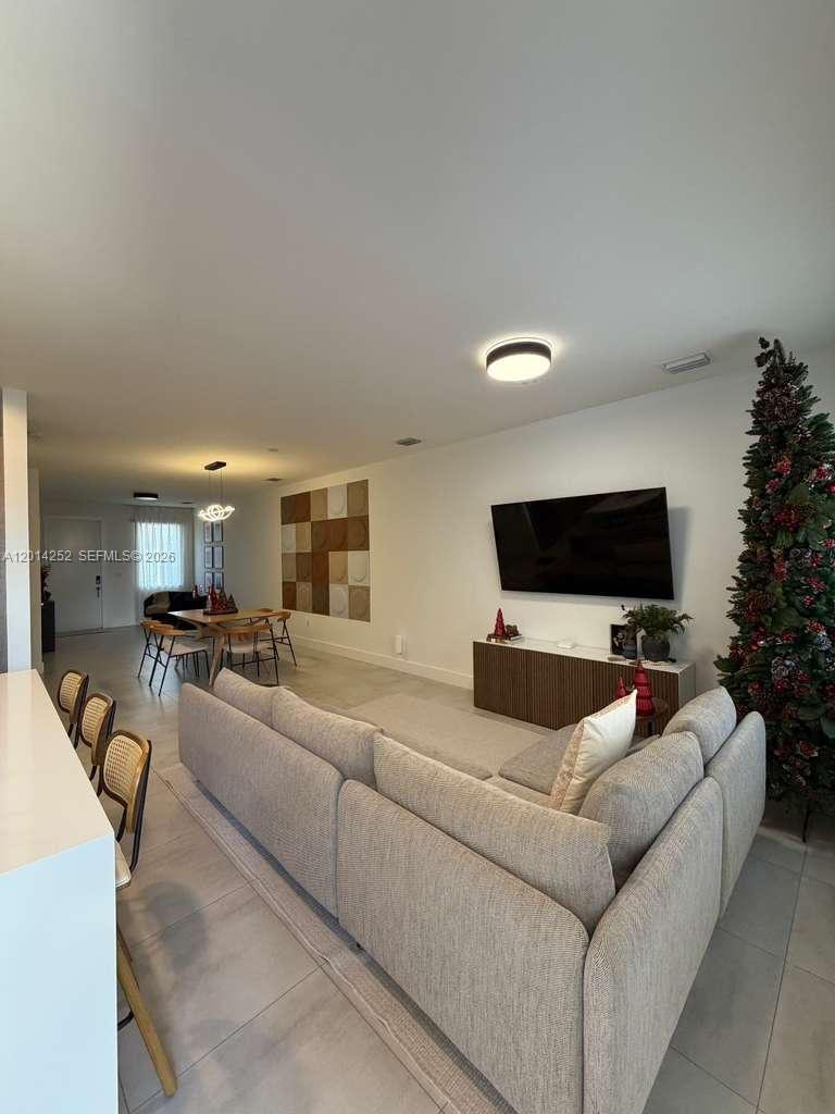 A living room features a sectional sofa, a wall-mounted television, and a dining area — 7187 NW 103 PATH # 7187, Miami FL 33178, MIAMI, FL