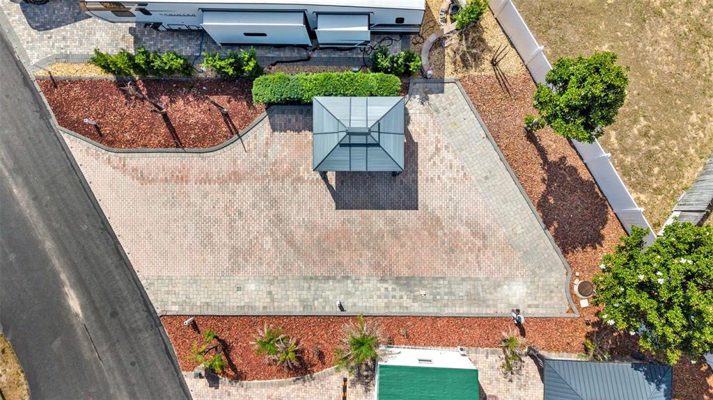 An aerial view shows a paved patio area featuring a gazebo, landscaping, and a trailer — 2320 LIMEWOOD AVENUE, CLERMONT, FL