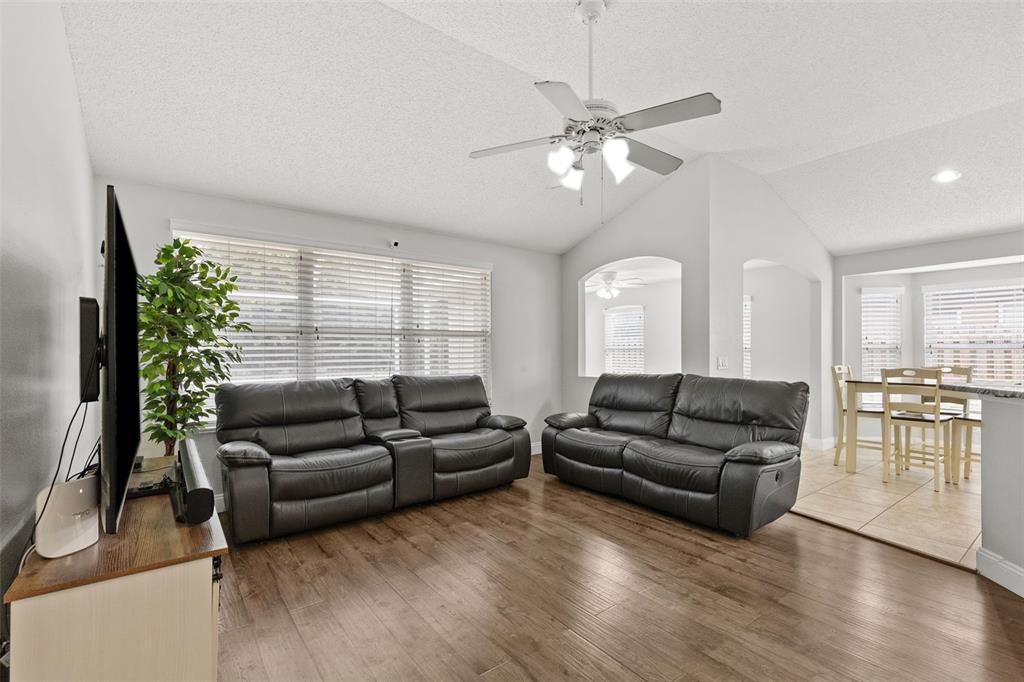 A living room with wood-look flooring, two dark leather sofas, and a ceiling fan — 4508 NEW DAWN COURT, LUTZ, FL