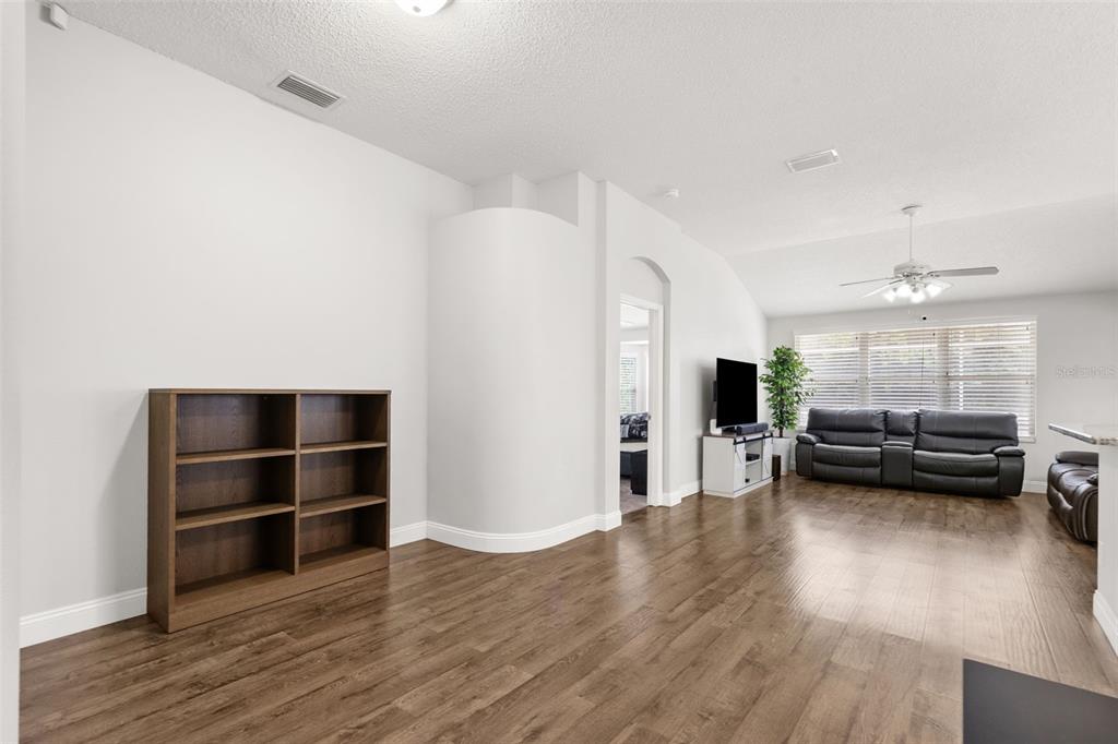 A living room with wood-look flooring, a dark wood bookshelf, and a leather sofa — 4508 NEW DAWN COURT, LUTZ, FL