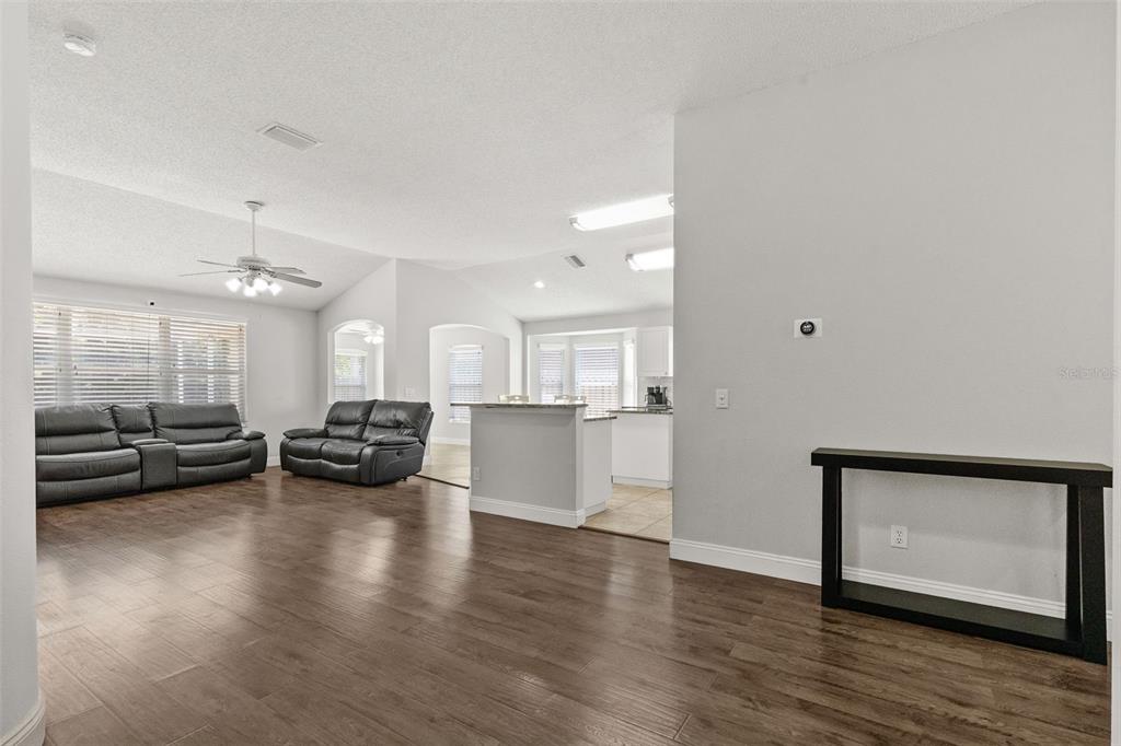 An open-concept living room with wood-look flooring, gray walls, and a kitchen in the background — 4508 NEW DAWN COURT, LUTZ, FL